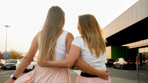 Rear view photo of two blonde girls embracing and olding each other at sunset — Stock Photo, Image