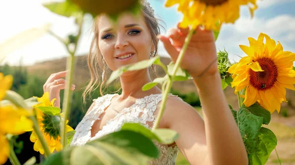 Porträtt av vacker elegant blond brud poserar med solrosor på fältet — Stockfoto