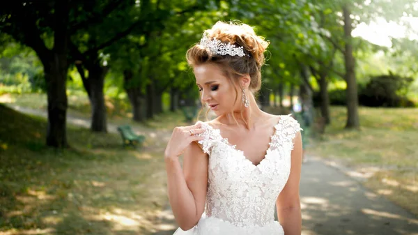 Beautiful sexy young bride posing in park under high trees on long alley — Stock Photo, Image