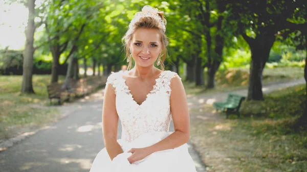 Toned portret van mooie blonde bruid in witte bruidsjurk wandelen in park — Stockfoto