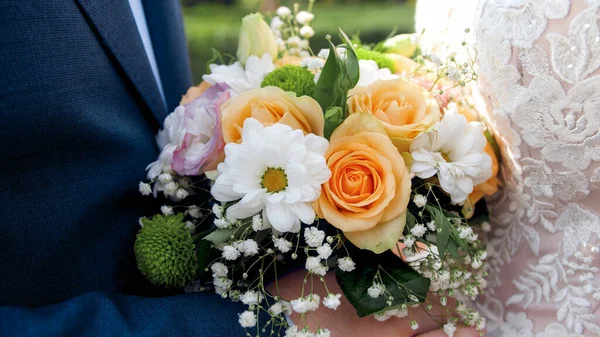 Closeup image of newly married couple holding beautiful wedding bouquet — Stock Photo, Image