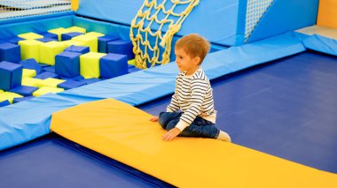 Sevimli küçük çocuk lunaparkta trambolinlerde oynayıp eğleniyor.