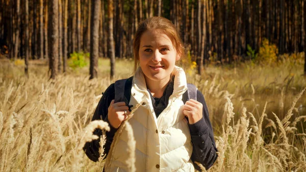 Retrato de hermosa chica sonriente con mochila senderismo en el bosque en el cálido día de otoño —  Fotos de Stock