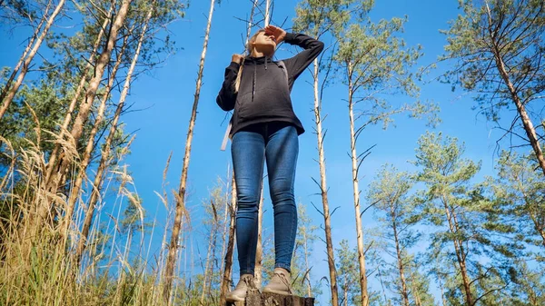 Young female hiker protecting her eyes from bright sun with hand and looking far away — Stock Photo, Image