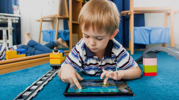 Porträtt av leende pojke med hjälp av pad dator för att spela spel — Stockfoto