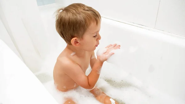 Little toddler boy sitting in bath and playing with soap foam — Stock Photo, Image