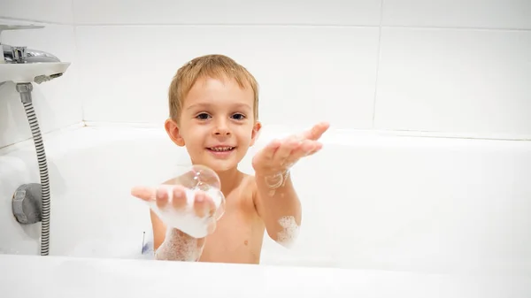 Banyo yapan tatlı çocuk portresi uçan sabun köpükleri. — Stok fotoğraf