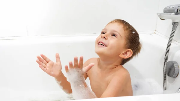 Retrato de niño sonriente alegre disfrutando lavándose en el baño con espuma de jabón — Foto de Stock