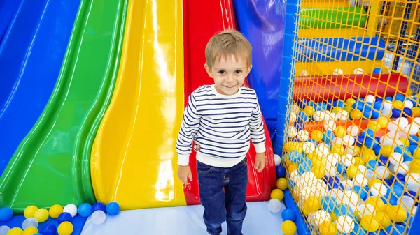 Porträtt av glad leende liten pojke står i lekrum med färgglada bild på nöjespark — Stockfoto