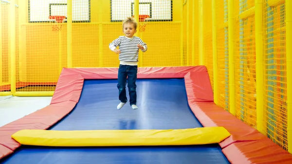 Boldog aktív kisfiú ugrás magas trambulin palyroom a bevásárlóközpontban — Stock Fotó
