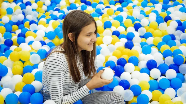 Porträtt av leende tonåring flicka föll i gropen med mjuka färgglada bollar på lekplatsen i köpcentret — Stockfoto