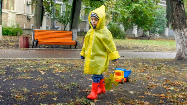 Droevig jongetje in regenjas wandelen in het najaarspark op regenachtige herfstdag — Stockfoto