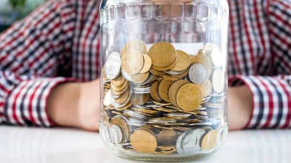 Homme assis avec un bocal en verre plein de pièces. Concept de finance, de croissance économique et d'épargne bancaire — Photo