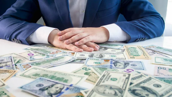 Hombre de negocios cogido de la mano en el escritorio cubierto de dinero. Concepto de inversión financiera, crecimiento económico y ahorro bancario — Foto de Stock