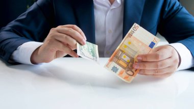 Avro ve dolar banknotları elinde tutan işadamı.