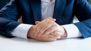 Mavi takım elbiseli bir işadamının beyaz ofis masasına tutunduğu yakın plan.