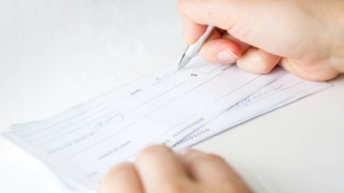 Aylık ödemeler ve vergiler için banka çekleri dolduran adam