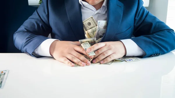 Codicioso hombre de negocios rico llenando sus bolsillos con dinero . —  Fotos de Stock