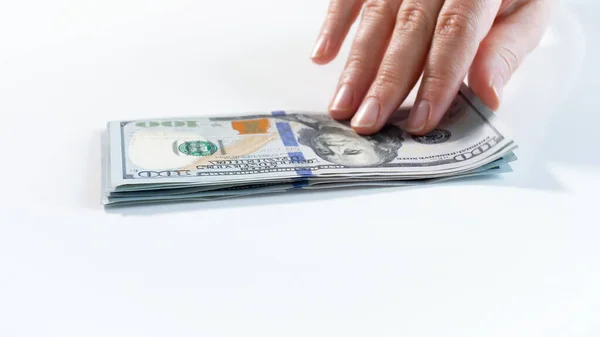 Yakından bakınca, beyaz masadaki para yığınından dolar banknotu alan el resmi. — Stok fotoğraf