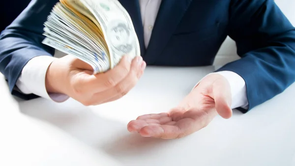 Young businessman slapping his hand with stack of money. Concept of financial investment, economy growth and bank savings — Stock Photo, Image