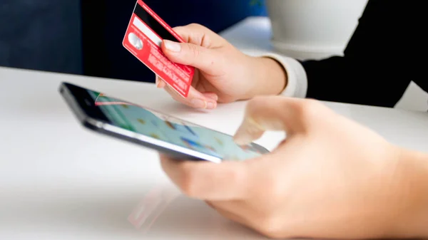 Młoda kobieta trzymająca kartę kredytową podczas zakupów online na smartfonie. Pojęcie zakupów internetowych i handlu elektronicznego — Zdjęcie stockowe