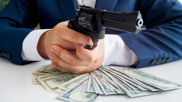 Closeup image of businessman with wad of cash aiming with gun — Stock Photo, Image