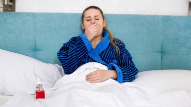 Genç hasta kadın öksürüyor ve elleriyle ağzını kapıyor.