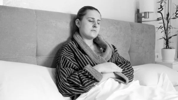 Yatakta yatan ve vücut ısısını ölçen hasta genç kadının siyah beyaz portresi. — Stok fotoğraf