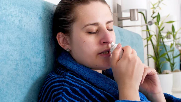 Detailní fotografie nemocné ženy chycené nachlazení pomocí nosní sprej v nose — Stock fotografie
