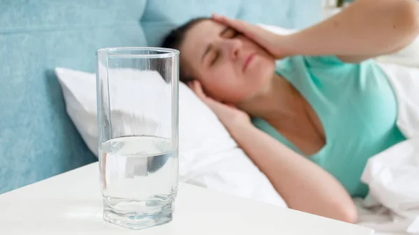 Mladá žena trpící migrénou ležící v posteli — Stock fotografie