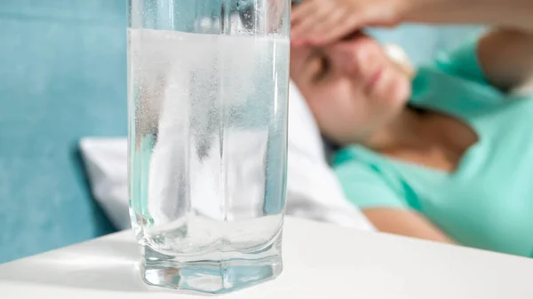 Szoros kép a törekvő fájdalomcsillapító oldódásáról egy pohár vízben az éjjeliszekrényen — Stock Fotó