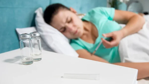 Imagen borrosa de una mujer enferma con diabetes acostada en la cama y fabricando insulina inyectable con jeringa —  Fotos de Stock