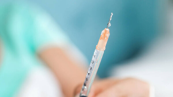 Closeup image of droplets of medicines on the syringe needle edge