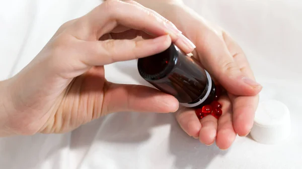 Zieke vrouw gieten pillen en tabletten bij de hand uit glazen fles — Stockfoto