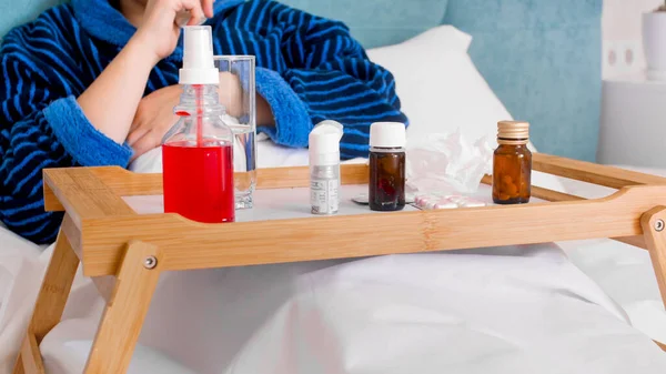 Imagem de close-up de muitos medicamentos na bandeja de madeira na cama da mulher doente — Fotografia de Stock