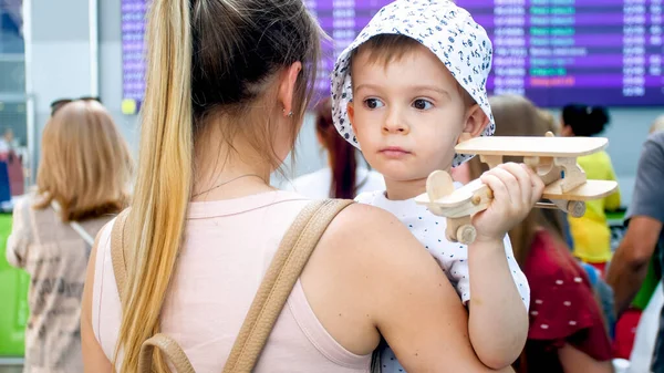 Portrait de triste petit garçon embrassant mère à l'aéroport et tenant jouet avion — Photo