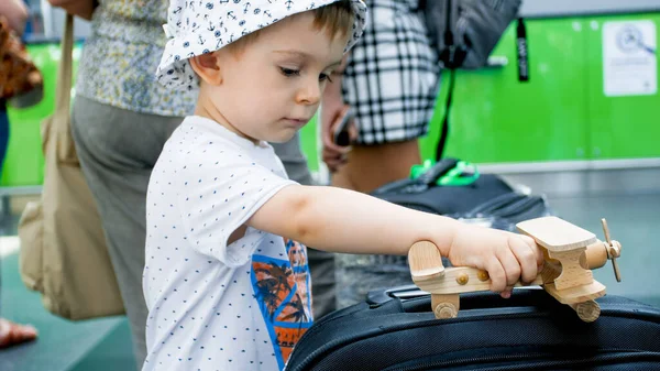 Portrait d'un petit garçon jouant avec un avion jouet en bois dans un terminal aéroportuaire moderne — Photo