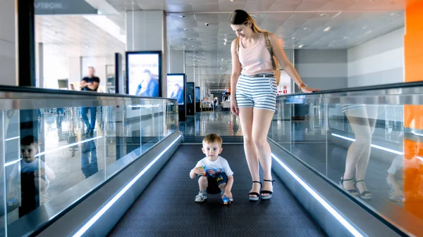 Petit garçon avec jeune mère debout sur l'escalier roulant horizontal au terminal de l'aéroport — Photo