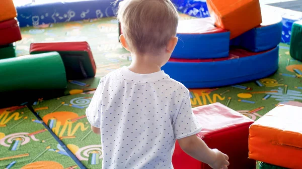 Hátsó nézet kép a kis csecsemő fiú játszik a játszótéren, puha tárgyak — Stock Fotó