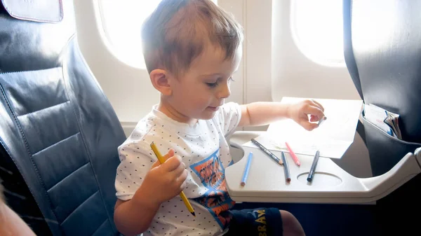 Retrato de niño sonriente dibujando con lápices durante el vuelo en avión — Foto de Stock