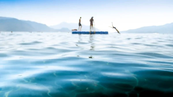 Foto borrosa de niños saltando del pontón al agua del mar —  Fotos de Stock