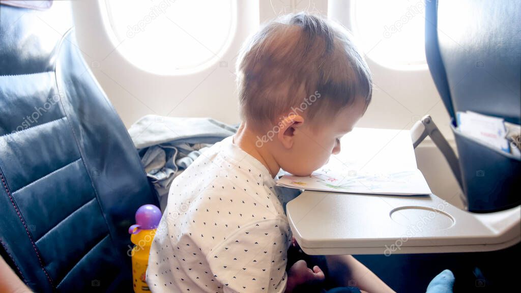 Portrait of bored little toddler boy during long flight in airplane