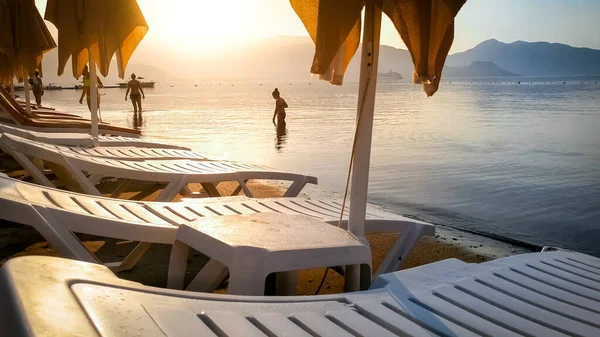 Coucher de soleil Beautfiul sur les chaises longues sur la plage de la mer et l'eau de mer calme — Photo