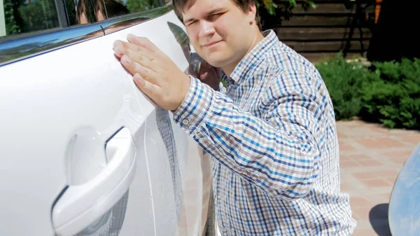 Πορτρέτο του χαρούμενου χαμογελαστού οδηγού κοιτάζοντας το νέο του αυτοκίνητο και κρατώντας το χέρι στην πόρτα — Φωτογραφία Αρχείου