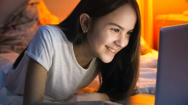 Happy uśmiechnięta nastolatka przeglądająca internet i czatująca na laptopie w nocy — Zdjęcie stockowe