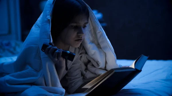 Retrato de linda chica que cubre con manta y libro de lectura con antorcha de luz — Foto de Stock