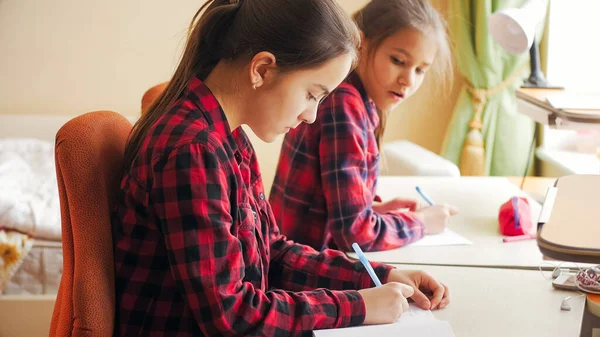 Duas adolescentes no auto-isolamento estudando em casa e fazendo lição de casa da escola — Fotografia de Stock