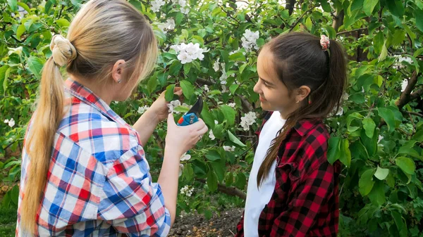 Yougn moeder onderwijs tiener meisje snijden takken en het verzorgen van de tuin — Stockfoto