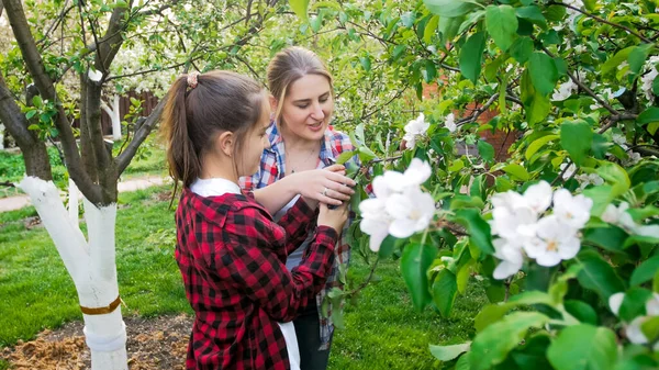 Portret van een jonge moeder met tienerdochter die in de tuin werkt en voor de bomen zorgt — Stockfoto