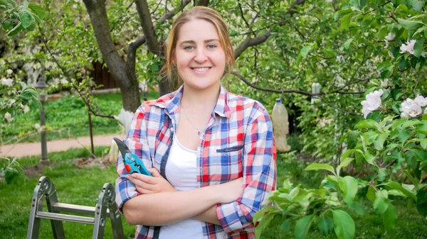 Portret van een vrolijke glimlachende jonge vrouw poserend in een bloeiende boomgaard — Stockfoto